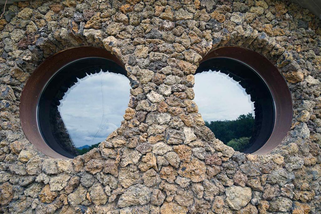 Dos ventanas circulares rodeadas por el muro de piedra de La Casa Verda.