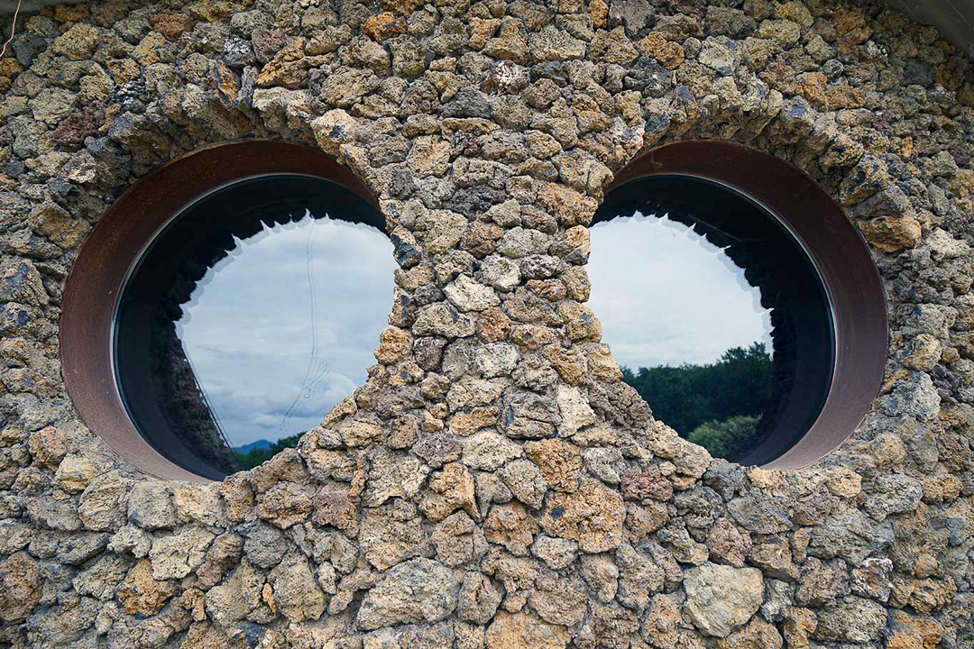 Dos ventanas circulares rodeadas por el muro de piedra de La Casa Verda.